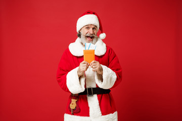 Excited elderly gray-haired mustache bearded Santa man in Christmas hat posing isolated on red background. Happy New Year 2020 celebration holiday concept. Mock up copy space. Holding passport ticket.