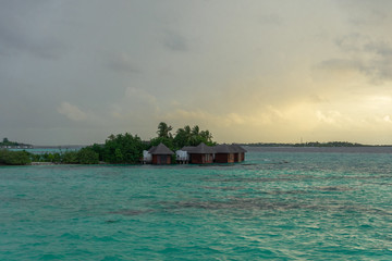 Separate view of a tropical island with turquoise sea, coconut palm trees and blue sky in the Maldives. Indian Ocean Sunset