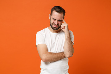 Dissatisfied upset young man in casual white t-shirt posing isolated on orange background studio...
