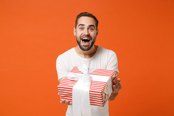 Excited young man in white t-shirt posing isolated on orange background. Valentine's Day Women's...