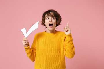 Shocked young brunette woman girl in yellow sweater posing isolated on pastel pink background....