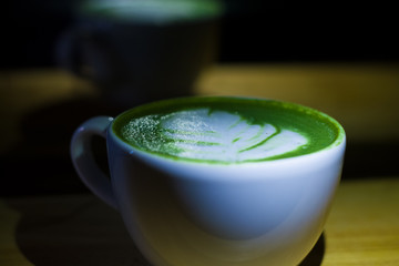 White ceramic cup with green matcha latte. Milk and shaved Japanese tea. Useful drink for health.