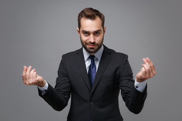 Young business man in classic suit shirt tie posing isolated on grey background. Achievement career wealth business concept. Mock up copy space. Rubbing fingers showing cash gesture asking for money.