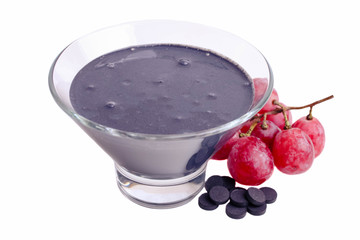Black yogurt in a bowl with red grapes and activated carbon tablets