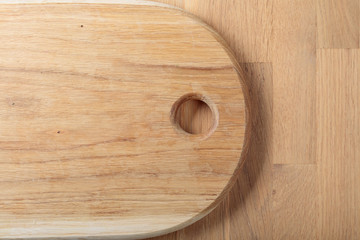Wooden cutting board with circle hole on a oak table. Top view.