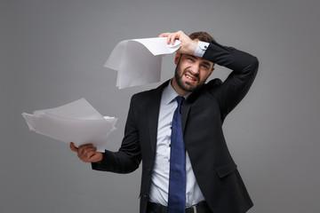 Tired young business man in classic black suit shirt tie posing isolated on grey background....