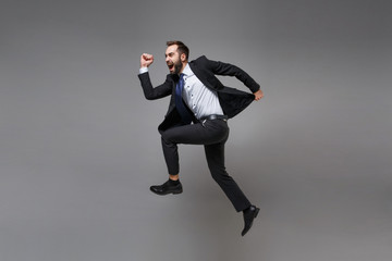 Fototapeta na wymiar Side view of crazy young business man in classic suit shirt tie posing isolated on grey background. Achievement career wealth business concept. Mock up copy space. Jumping, running, fooling around.