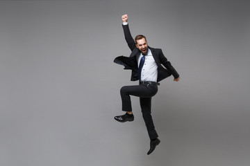 Happy young business man in classic black suit shirt tie posing isolated on grey background....
