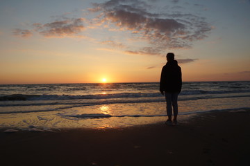 woman looking over the water at the sunset