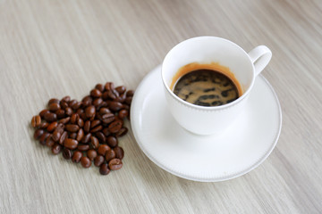 Cup of coffee and coffee beans on the table.