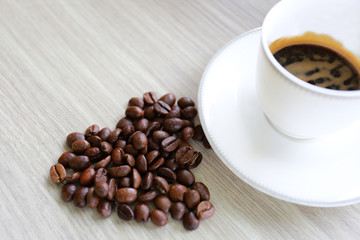 Cup of coffee and coffee beans on the table.