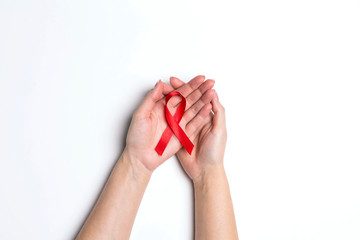 Red AIDS ribbon awareness on woman hands on white background.