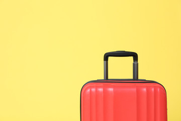 Stylish red suitcase on yellow background. Space for text