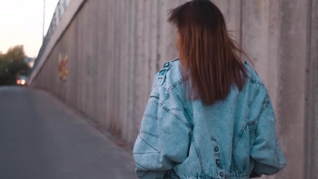 Young woman in blue denim jaket walking. Stylish Fashion Blogger Walking Along Urban Street