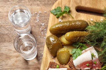 Cold Russian vodka with snacks on wooden table, above view