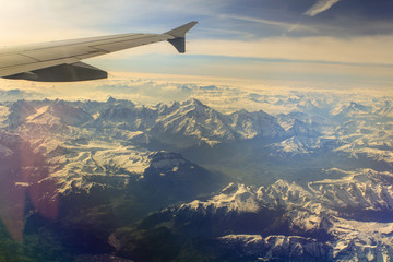 View from the plane on the snow capped mountain peaks stretching into the distance