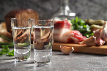 Cold Russian vodka with snacks on grey table, closeup