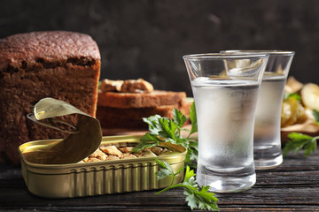 Cold Russian vodka with snacks on black wooden table, closeup
