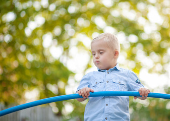 The daily life of a child with disabilities. A boy with Down syndrome plays in the playground....
