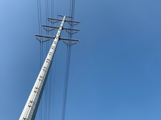 Obraz premium Metal power tall tower with high-voltage cables against the clear blue sky and sunlight.
