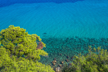Aerial view from above amazing colorful sea water and bright green trees growing at hill. Aegean sea transparent perfect water. Horizontal color photography.