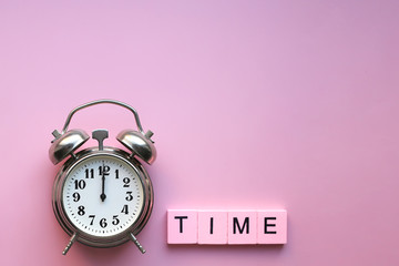 Retro alarm clock and time word, on pink background. The concept of time, holiday, deadline. Layout with copy space for your text.