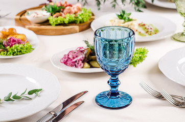 Empty glasses set in restaurant. Served for holiday banquet restaurant table with dishes, snack, salads, cutlery, wine and water glasses. European food