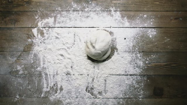 woman throws dough onto table surface with flour slow motion