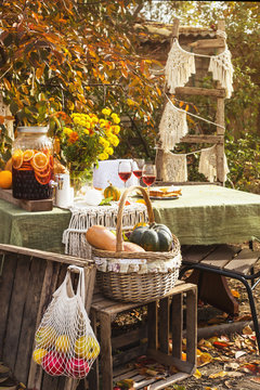 Beautiful festive dinner in the garden among autumn leaves and pumpkins with wine and different pies. Thanksgiving day concept.