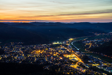 Fototapeta premium Germany, Black forest village skyline of haslach im kinzigtal houses, streets, cityscape illuminated by night, aerial view from above with red sky, a perfect nature landscape