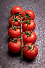 Tomatoes panicles with water drops on a dark stone board