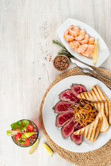 Roast beef with shrimp and drink on a wooden background