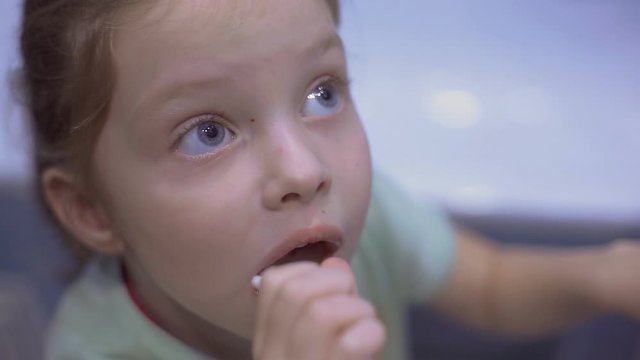 Little girl f brushing her teeth with a toothbrush in bathroom in the morning.
