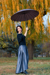 Beautiful elegant woman standing and posing with umbrella in autumn city park