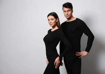 Couple wearing thermal underwear on light grey background. Space for text