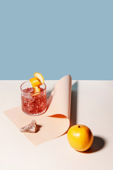 Summer cocktail with orange. Colorful background with pastel colors, blue and beige separated.  Curves paper as a basis. Abstract studio conception.
