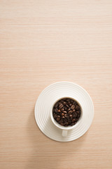 Cup of full coffee beans on the wood background