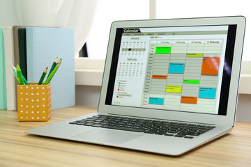 Modern laptop with calendar on screen in office
