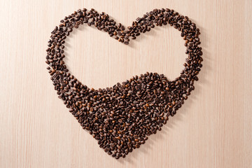 heart shape made of coffee beans on wooden background