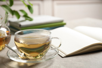 Tasty hot green tea in cup on grey table