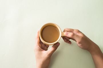 Hands holding cups of coffee on color background