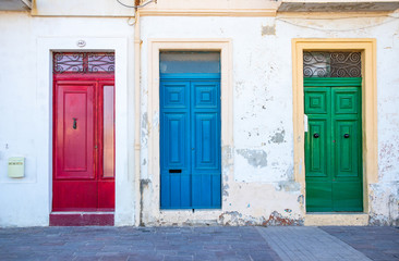 Three typical traditional maltese doors in Marsaxlokk village. Red, blue, green doors. Morning. Malta