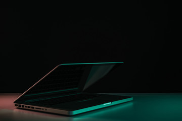 Beautiful silver laptop in the color light on a table and night background.