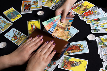 Bangkok,Thailand,november.22.19.Payment for esoteric, magical and witchcraft services in Kazakhstan in the national currency Tenge. Payment with Tengu money on a black background with Tarot cards