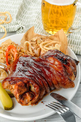 Knuckle on a white plate, next to a light beer