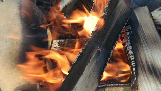 Flame of a burning bonfire from dry logs is swaying in the wind, background