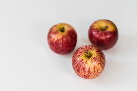 Fresh red yellow striped apples with water droplets on a white glossy kitchen table. Tasty bright juicy fruits. Healthy eating Isolated object	