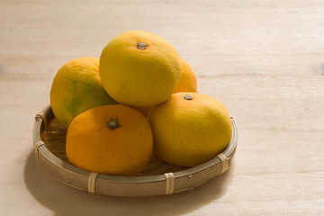 ザルに入ったミカン　木目背景　