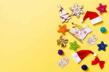 Top view of Christmas decorations and Santa hats on yellow background. Happy holiday concept with copy space
