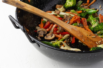 a pan with skipped vegetables and seeds, and a wooden spatula